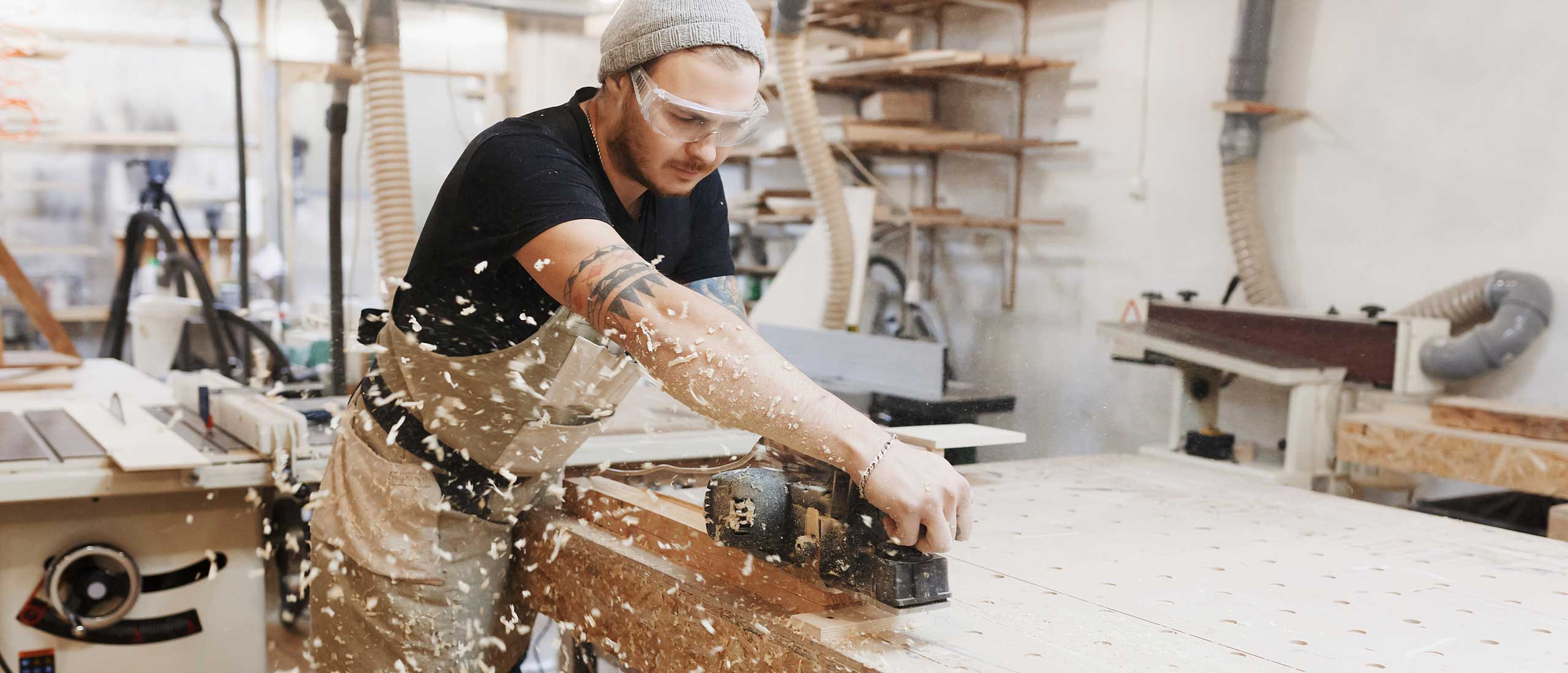 Holzarbeiter mit Elektrohobel bearbeitet Holz in einer Werkstatt