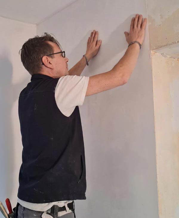Arbeiter tapeziert eine Wand